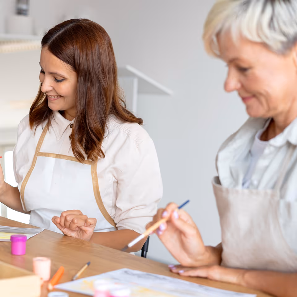 A younger woman painting beside an older woman