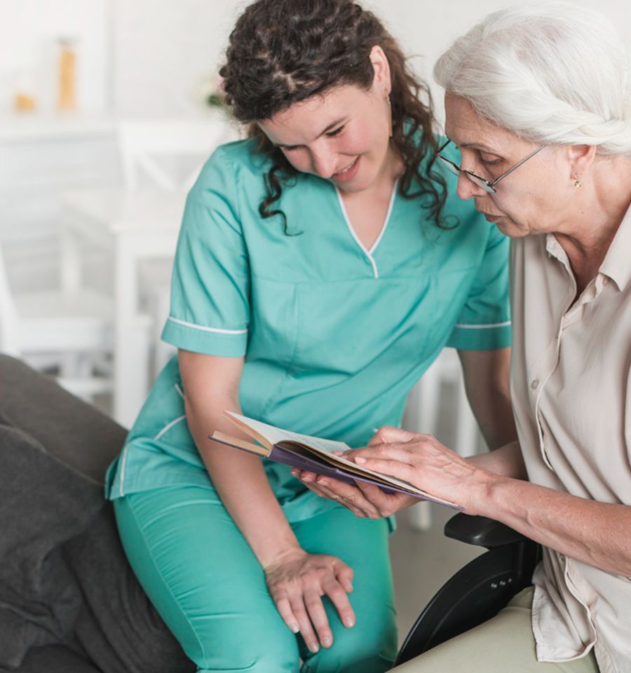 A caregiver reading with an older woman at home